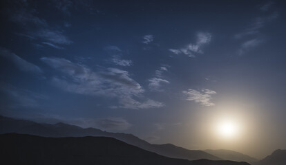Night landscape in the mountains with a full moon and starry sky for background in the mountains of Tajikistan