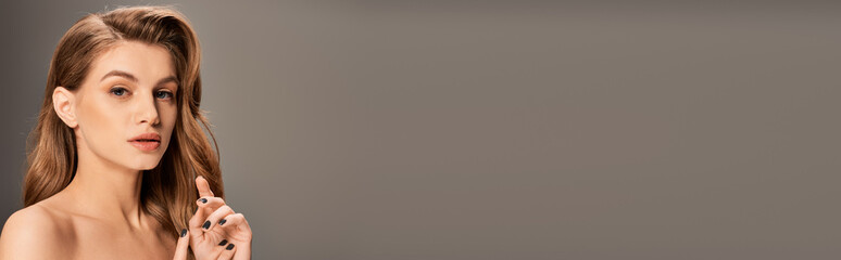 A stunning young woman with wavy long hair poses gracefully for a portrait, banner.