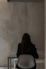 A young woman working on a laptop at her desk in her studio