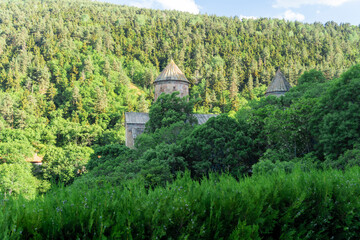 Fototapeta premium The domes of the churches of the Sapara monastery illuminated by the sun among the trees
