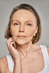 Mature woman in comfortable attire strikes a thoughtful pose, resting chin on hand.