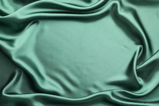 Crumpled green silk fabric as background, top view