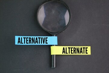 magnifying glass and two colored papers with the words alternative or alternate