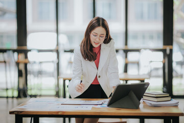 Attractive Asian businesswoman working at modern office with balance sheet documents. Accounting