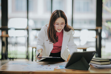 Attractive Asian businesswoman working at modern office with balance sheet documents. Accounting