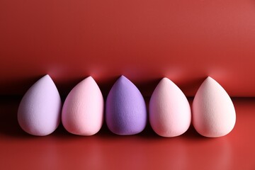 Many colorful makeup sponges on red background