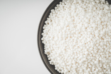 White Sago Pearls in Dark Bowl Also Know as Sabudana, Tapioca Pearl or Sago Seeds isolated on White Background. Top view