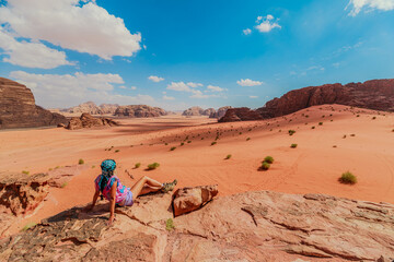 Lone traveler sits on a rock, overlooking the expansive Wadi Rum desert in Jordan under a vast blue sky, embodying peace and adventure in the mesmerizing middle eastern landscape of Jordan