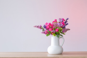 beautiful flowers in white jug on wooden shelf
