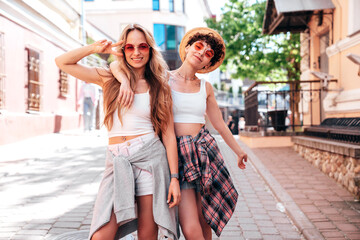 Naklejka premium Two young beautiful smiling hipster female in trendy summer white t-shirt and shorts clothes. Sexy carefree women posing in the street. Positive models having fun, hugging and going crazy