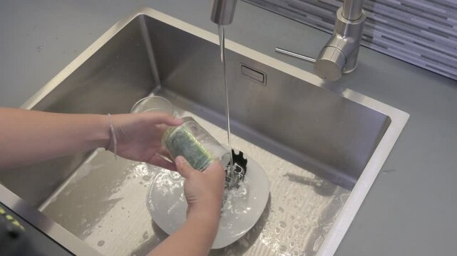 Washing dishes with a sponge in a kitchen sink