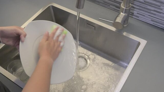 Washing dishes with a sponge in a kitchen sink