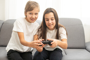 Two sisters kids playing video games at home together. Happy childeren, carefree childhood concept