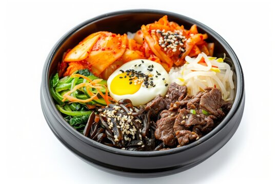 Delicious Korean bibimbap with vegetables, beef, and a fried egg, seasoned with sesame seeds in a black bowl, isolated on white background.