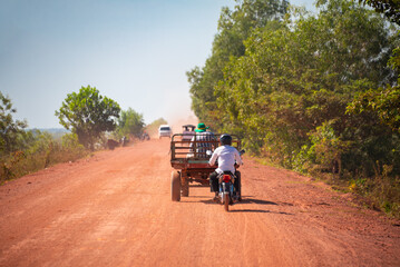 Obraz premium Country dirt road of red sand in Cambodia with bikes