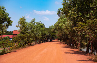 Red sand dirt road among forest in Cambodia countryside