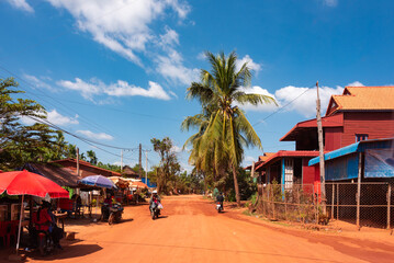 Country red sanddirt road and village in Cambodia countryside