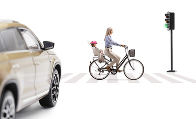 Naklejka premium Woman riding a bicycle with a child in a back seat in front of a vehicle at pedestrian crossing