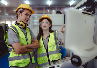 Two industrial engineer operating modern technology CNC machine in metalwork manufacturing....