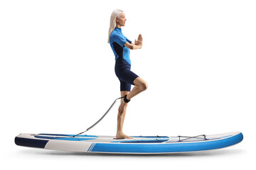 Full length profile shot of a woman exercising yoga on a paddle board