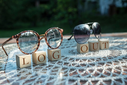 okulary słoneczne w słońcu na tle zieleni z napisem log out