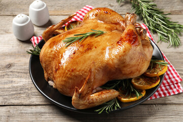 Tasty roasted chicken with rosemary and lemon on wooden table