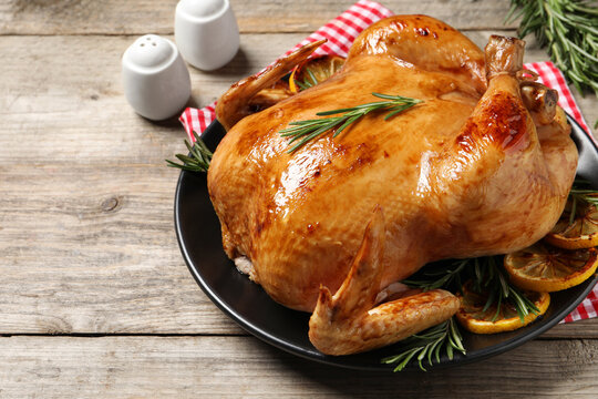 Tasty roasted chicken with rosemary and lemon on wooden table