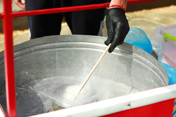 Man making cotton candy with machine outdoors, closeup