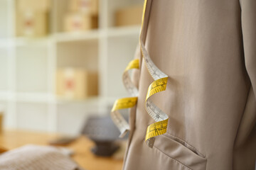 Mannequin with beige jacket and measuring tape in tailor shop, space for text