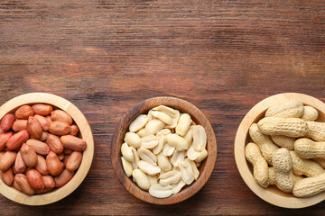 Fresh peanuts in bowls on wooden table, top view