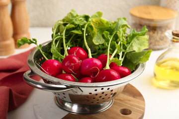 Wet radish in colander on white table, closeup