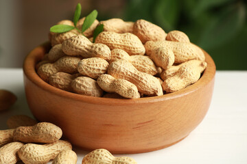 Fresh unpeeled peanuts in bowl on white table