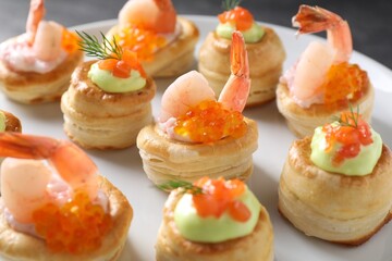 Different delicious puff pastry snacks on plate, closeup