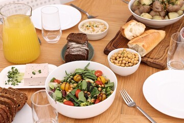 Healthy vegetarian food, glasses, cutlery and plates on wooden table