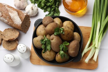 Tasty young boiled potatoes served on white table, flat lay