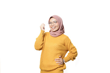 Excited Asian Muslim woman raising fists, celebrating victory with euphoric facial expression...
