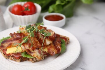 Tasty sandwich with bacon and microgreens on white marble table, closeup