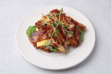 Tasty sandwich with bacon and microgreens on light grey table