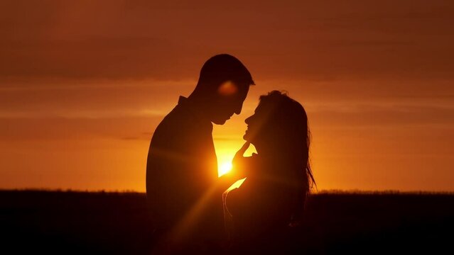 Silhouette, beach and couple at sunset kiss for bonding, together and relationship by ocean. Dating, nature and man and woman with affection and love for romance on honeymoon, vacation and weekend