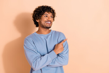 Portrait of optimistic middle eastern guy dressed blue pullover look directing at offer empty space...