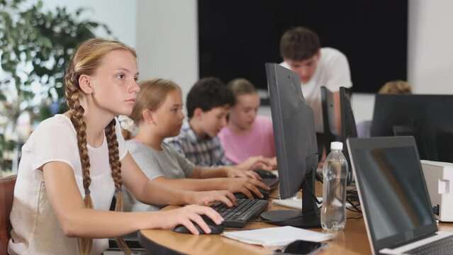 Girl student learning to use computer in group in classroom