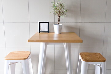 minimalist high table with two stools, small plant, photo frame, modern setting