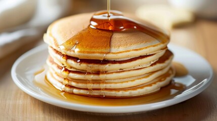 A plate of fluffy buttermilk pancakes stacked high and drizzled with maple syrup, a classic American breakfast favorite that's enjoyed any time of day