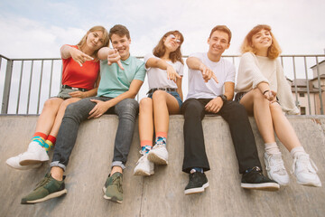 Obraz premium Summer holidays and teenage concept - group of smiling teenagers hanging out outside.