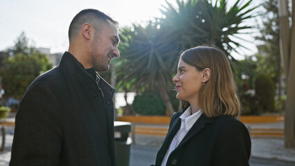 A loving couple exchange glances on a sunlit urban street, evoking a sense of romance and connection in the city.