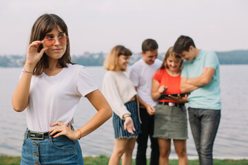 Happy teenage girl standing against the background of teenage friends hanging out on the street