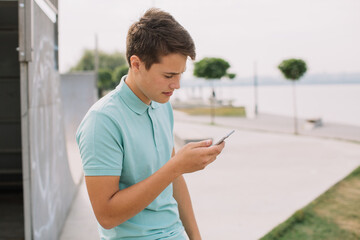 Technology, internet and people concept - happy teenage boy with smartphone outdoors.