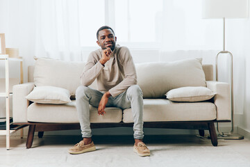 Sadness and Solitude A Thoughtful African American Man Sitting on his Comfortable Sofa in a Modern...