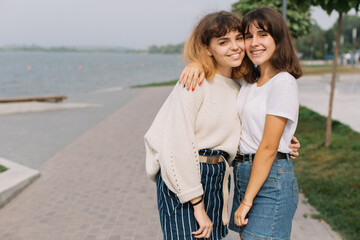 Two stylish teens schoolgirls joking and smiling togather on the street at school