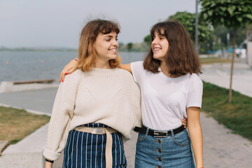 Two stylish teens schoolgirls joking and smiling togather on the street at school